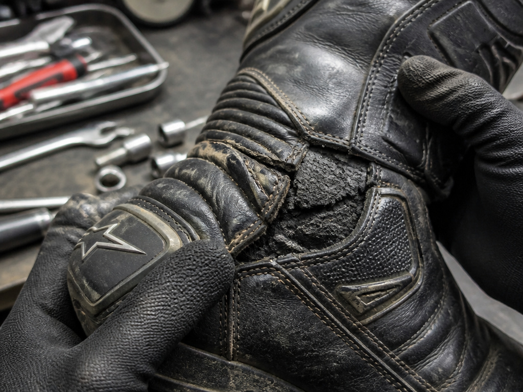 Close-up inspection of cracked leather on aging motorcycle boot
