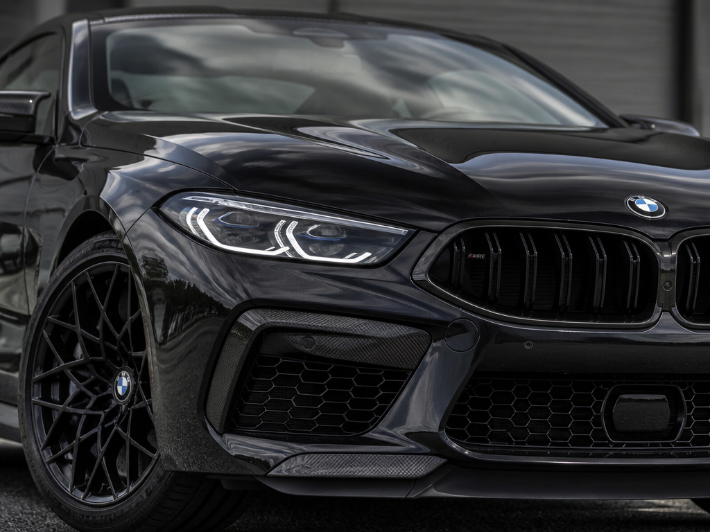 BMW M8 Competition Coupé front three-quarter view showing aggressive design and carbon fiber roof.